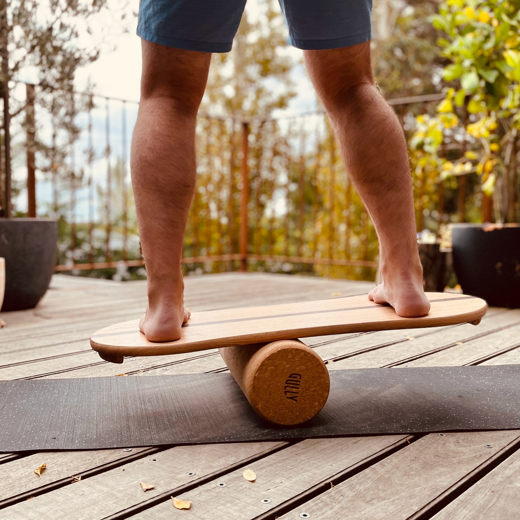 Man balancing on a handmade soild timber balance board with natural cork roller and recycled rubber mat